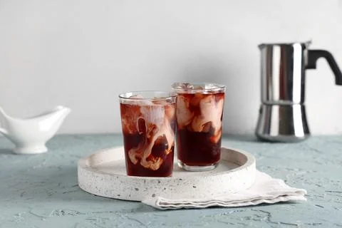 Two refreshing iced coffee drinks with cream swirls and ice cubes on a terraz Stock Photos