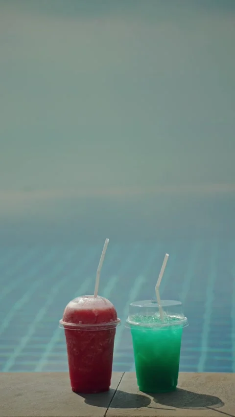 Two refreshing slushy drinks by poolside on a sunny day. Vídeo Stock 334906135