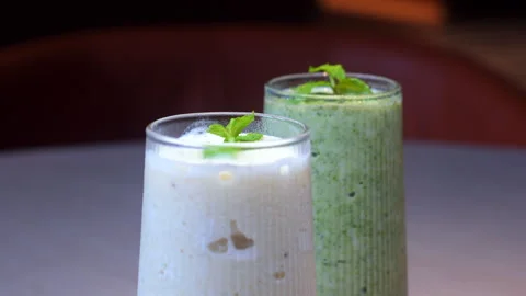 Two refreshing smoothies in tall glasses, garnished with fresh mint Stock Footage 283485826