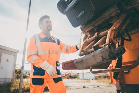Two refuse collection workers loading garbage into waste truck Stock Photos