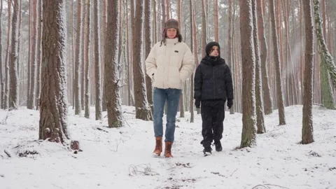 Two relaxed brothers strolling through a snowy forest on a calm winter day Stock Footage 312000894