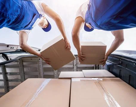 Two removal company workers unloading boxes from minibus Stock Photos