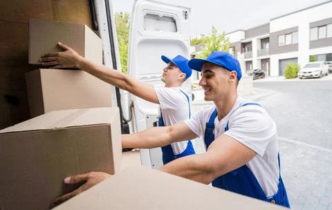 Two removal company workers unloading boxes from minibus Stock Photos