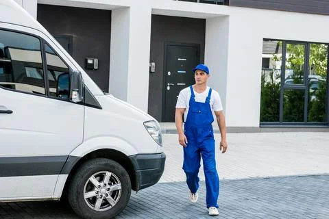 Two removal company workers unloading boxes from minibus into new home Stock Photos