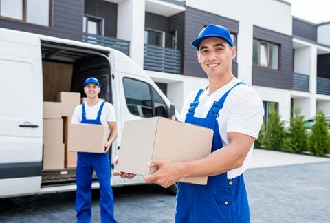 Two removal company workers unloading boxes from minibus into new home Stock Photos