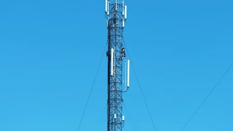 Two repairmen service a cell tower, install new cable and equipment Stock Footage 324682106