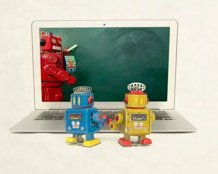 Two retro bobots learn about codeing on a laptop computer Stock Photos