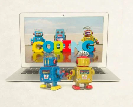 Two retro bobots learn about codeing on a laptop computer i Stock Photos