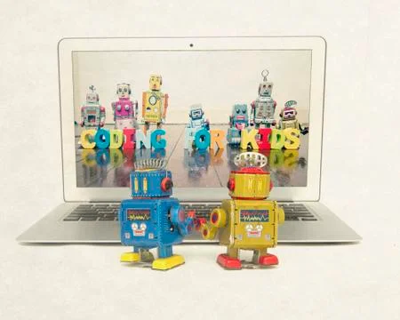 Two retro bobots learn about codeing on a laptop computer i Stock Photos