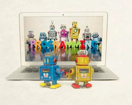 Two retro bobots learn about codeing on a laptop computer i Stock Photos