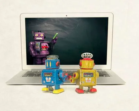Two retro bobots learn about codeing on a laptop computer Stock Photos