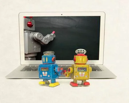 Two retro bobots learn about codeing on a laptop computer Stock Photos