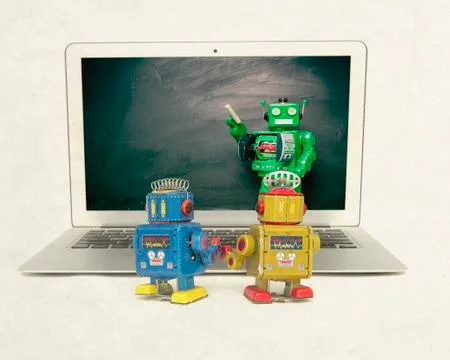 Two retro bobots learn about codeing on a laptop computer Stock Photos