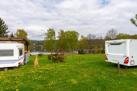 Two retro camper trailers parked on green grass near lake with wooden shelter Stock Photos