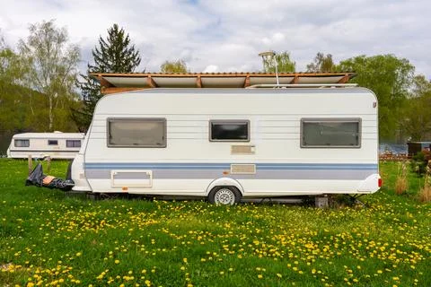 Two retro camper trailers parked on green grass near lake with wooden shelter Stock Photos