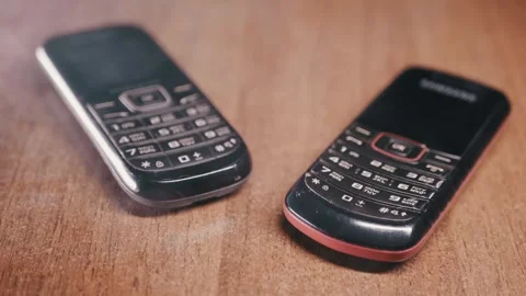 Two Retro Push Button Mobile Phones Lying On Brown Wood Table 库存影片 330110042