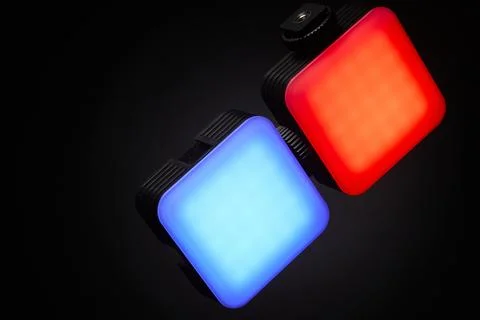 Two RGB LED panel lights glowing red and blue on dark background Stock Photos