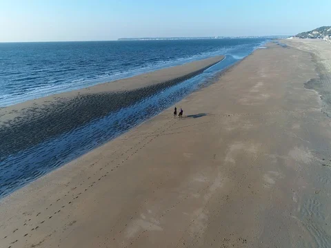 Two riders galloping over an empty stretch of beach Stock Footage 75069242