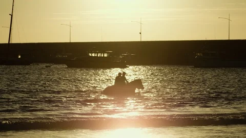 Two riders training their race horses at sunrise on Warrnambool beach. Stock Footage 92329935