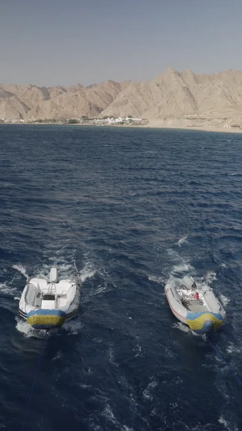 Two rigid inflatable boats towed by a larger vessel across the deep blue sea Stock-Footage 333694536