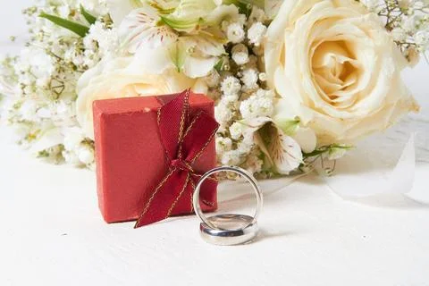 Two rings, different sizes, red box for rings, bridal bouquet on a white wo.. Stock Photos