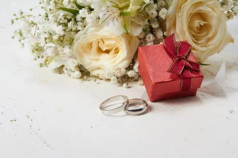 Two rings, different sizes, red box for rings, bridal bouquet on a white wo.. Stock Photos