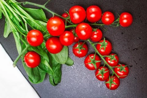 Two ripe branches of cherry tomatoes and a white linen towel with spinach on a Stock Photos