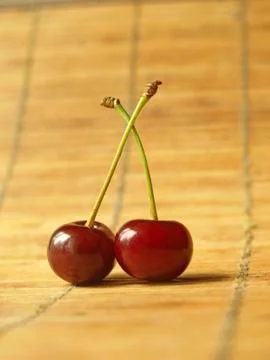 Two ripe cherry on bamboo surface. Stock Photos