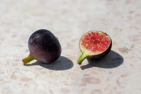 Two ripe figs placed side by side, one is cut open Stock Photos