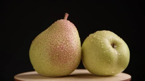 Two ripe juicy pears lie on a wooden surface on a black background Stock Footage