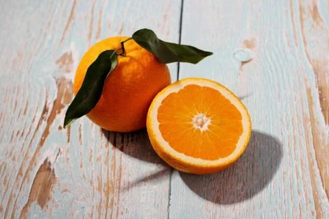 Two ripe orange fruit with leaf on wooden board Stock Photos