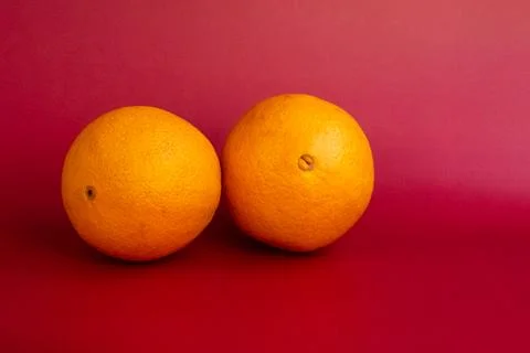 Two ripe oranges on a red background. Close-up, copy space Stock Photos