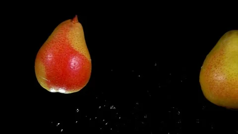 Two ripe pears are flying and colliding with drops of water on black background Stock Footage 289411766