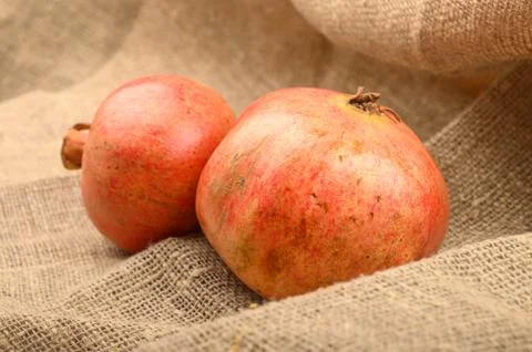 Two ripe pomegranates on a background of rough homespun fabric close-up. Fitn Stock Photos