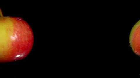 Two ripe red apples are flying towards each other on the black background Stock Footage 136480373