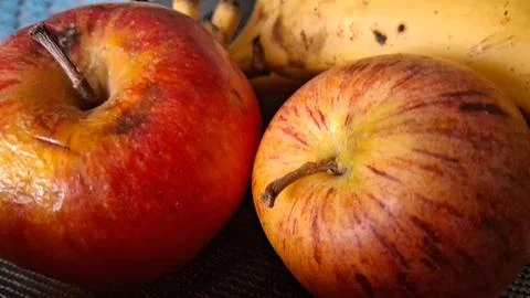 Two ripe red apples resting beside a yellow banana fruit Stock Photos