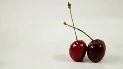 Two ripe, red cherries on a white background in motion Stock Footage 61218377
