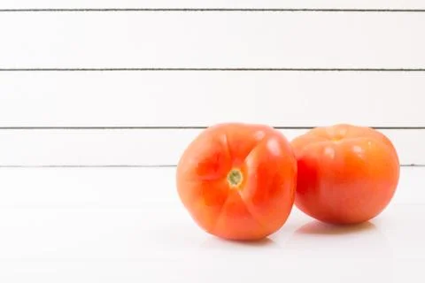 Two ripe tomatoes on a light background propped up Stock Photos