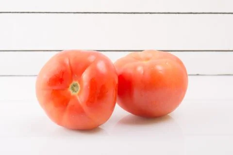 Two ripe tomatoes on a light background propped up Stock Photos