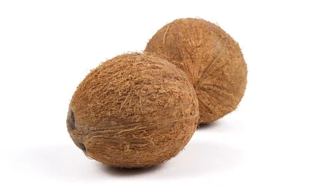 Two ripe whole tropical coconuts rotating on white background. Tropical fruits Stock Footage 86874864