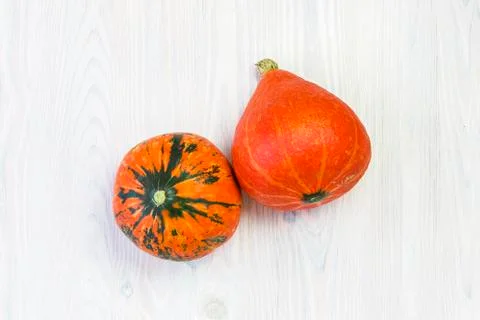 Two rippled beautiful pumpkins on a white wooden background with space for te Stock Photos