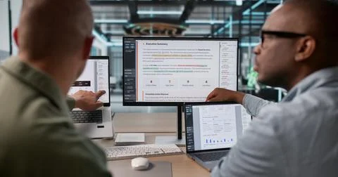 Two Risk Analysts Using Laptops To Review Detailed Enterprise Data Report. Stock Photos
