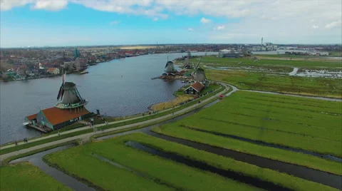 Two riverside windmills facing a Dutch mill town across water 库存影片 62162613