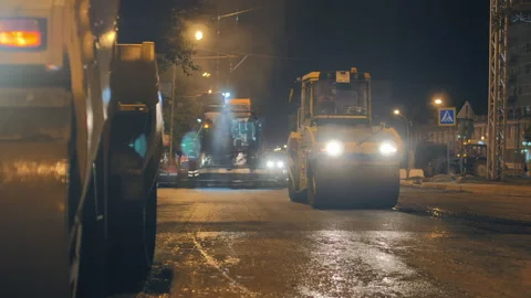 Two road rollers compact the asphalt in front of an asphalt paver. Repair of a Stock-Footage 152716101