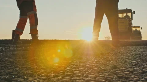 Two road workers in overalls level the fresh asphalt mix against the background Stock Footage 138910130