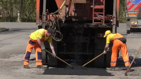 Two road workers shovel dry asphalt Stock Footage 153991122