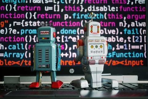 Two robots looking at laptop screen with source code, artificial intelligence Foto stock