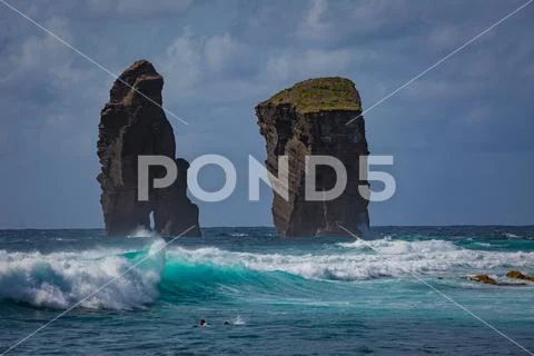 Two rocks in ocean water in rough sea waves Stock Photos
