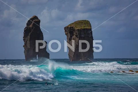 Two rocks in ocean water in rough sea waves Stock Photos
