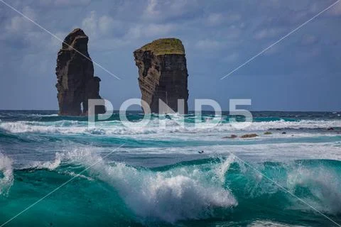 Two rocks in ocean water in rough sea waves Stock Photos